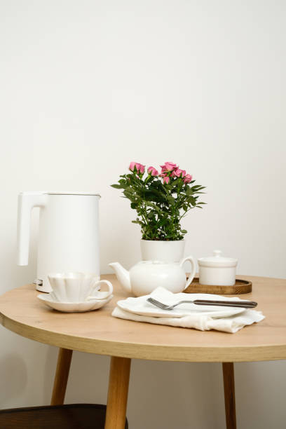 A beautifully serene dining table setting features an elegant flower pot, a lovely tea set, creating a cozy ambiance.