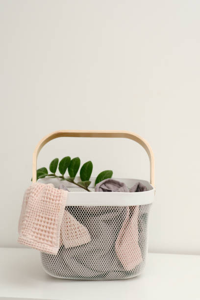 istock Basket with dirty laundry on white table against light wall 2196787972