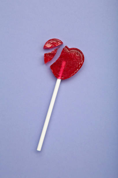 istock Broken heart lollipop on purple background. Vertical photo 2196789245