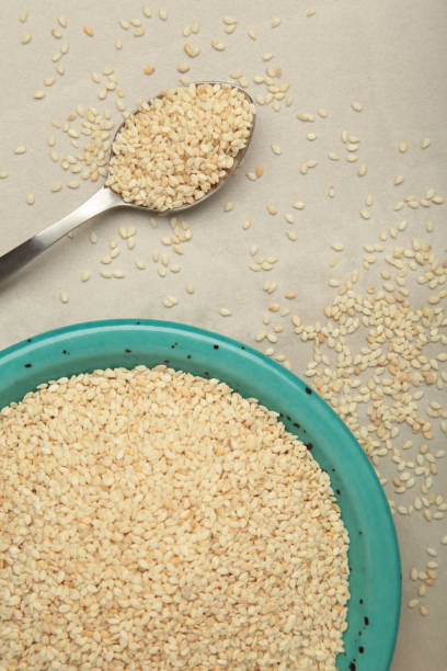 istock Raw sesame seeds in plate and spoon on light background. 2196789545