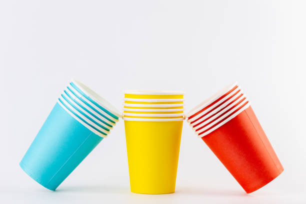 a white background a stack of paper cups for coffee and tea painted in red and blue rest on yellow disposable tableware for trips vacations and picnics eco cups waterproof house of cards