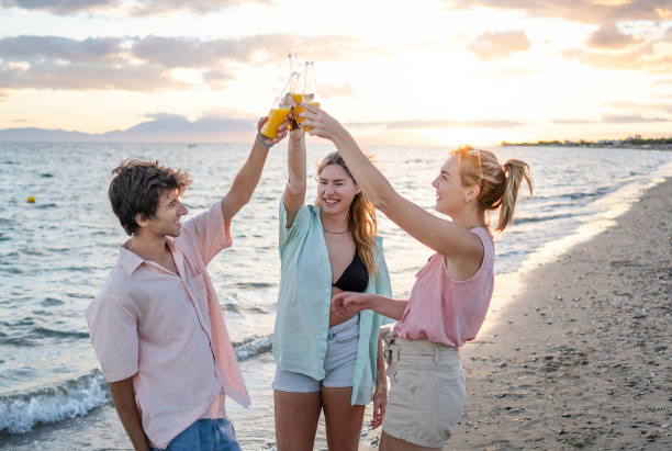 Happy friends toasting on the beach during sunset