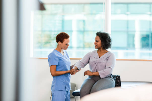 Young Asian nurse assisting middle-aged female patient on a couch doing physical therapy, focusing on muscle strengthening, rehabilitation, stretching,shoulder pain management in healthcare facility
