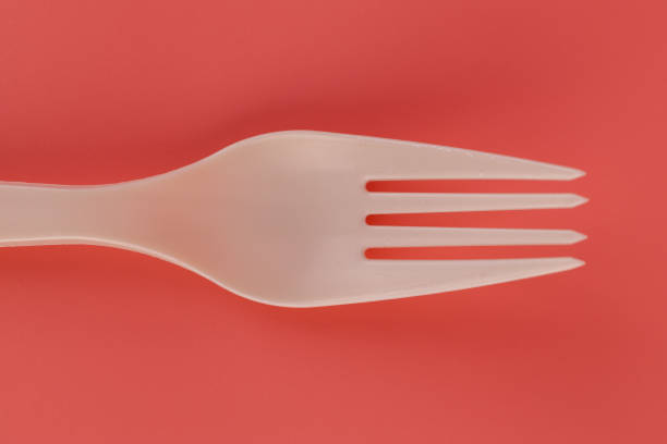 close up on soft pink background pair of plastic white forks disposable tableware eco technology reusable care for the planet picnic set