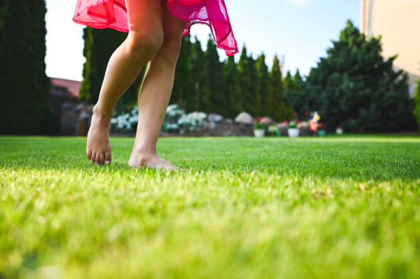 istock Low section barefoot girl on grass field. 2196799003