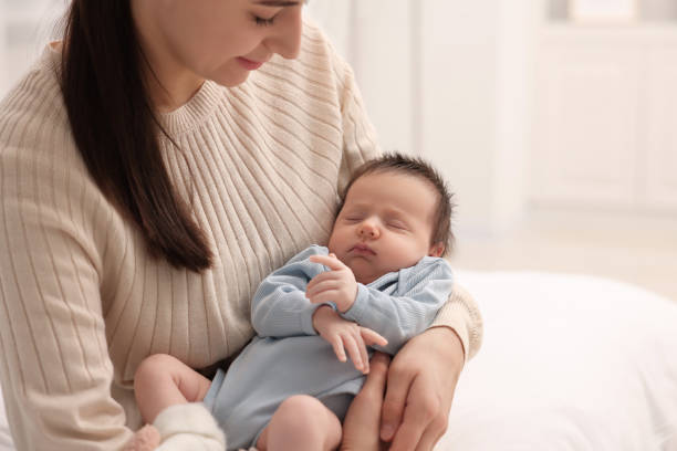 istock Mother with her sleeping newborn baby at home, closeup. Space for text 2196799576