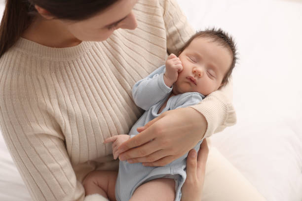 istock Mother with her sleeping newborn baby on light background, closeup 2196799598
