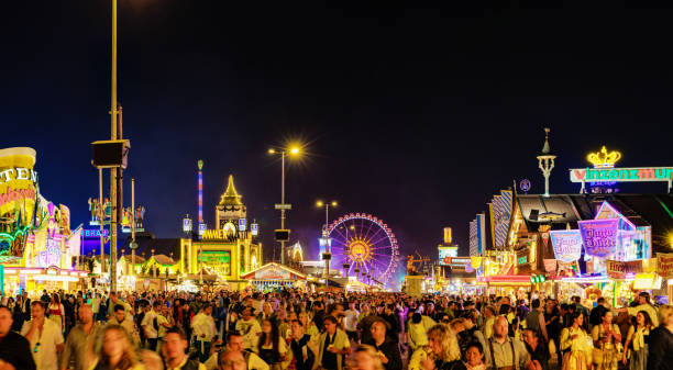 Das Oktoberfest erstrahlt bei Nacht mit bunten Lichtern, Fahrgeschäften und festlicher Stimmung, während tausende Besucher die einzigartige Atmosphäre genießen