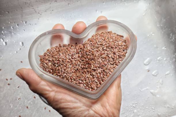 Heart shaped flax seeds on a plate in a person's hand