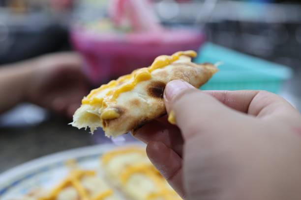 istock Close-up of hand holding cheesy naan bread slice. 2196802815