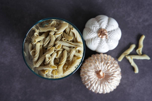 Composition with Italian pasta in a glass container on a dark background.