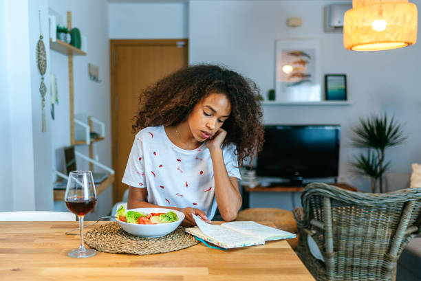 istock Woman at home reading notebook and eating salad and wine 2196804114