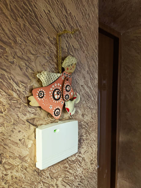Handcrafted hanging angel ornament on textured wall beside electronic device