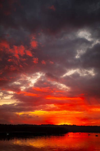 A vibrant sunset beautifully reflecting on the calm water, showcasing an array of hues and lovely clouds