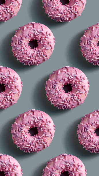 istock Pink donuts with colorful sprinkles, evenly arranged in a pattern on a gray background. Aesthetic sweet pattern for design. 2196809994