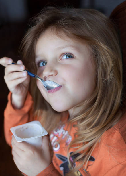 istock little happy girl eating yogurt 2196810397