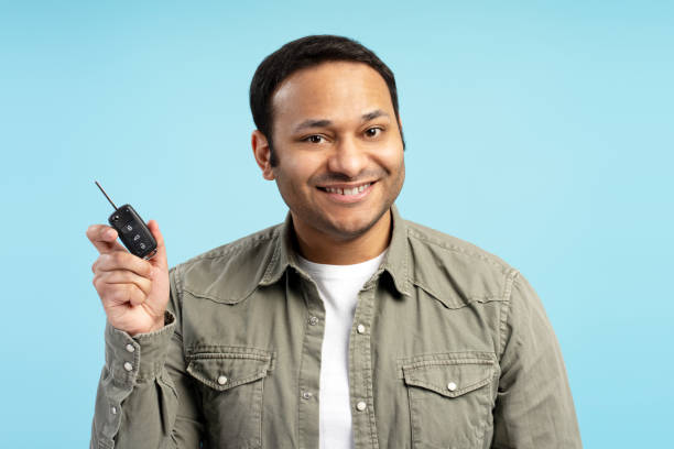 istock Happy man showing car key on blue background 2196815436