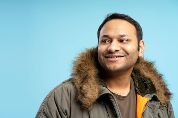 istock Smiling man wearing winter jacket looking away on blue background 2196818452