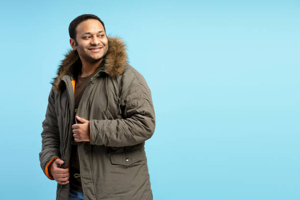 istock Smiling man wearing winter coat looking away on blue background 2196818456