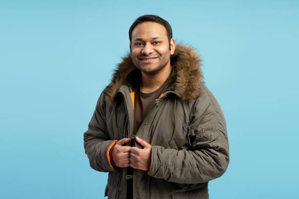 istock Smiling man wearing winter jacket on blue background 2196818464