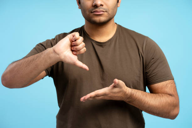 istock Man gesturing thumbs down and showing empty hand on blue background 2196818476