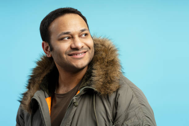istock Smiling man wearing winter coat looking away on blue background 2196818497