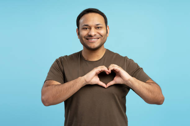istock Middle aged Indian man making heart shape with hands, smiling on blue background 2196818524