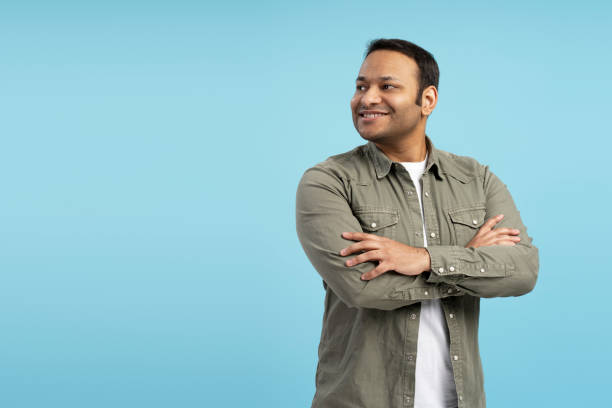 istock Confident indian man smiling and looking away on blue background 2196818530