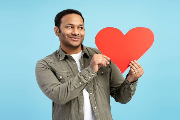 istock Happy man showing red heart against blue background 2196818560