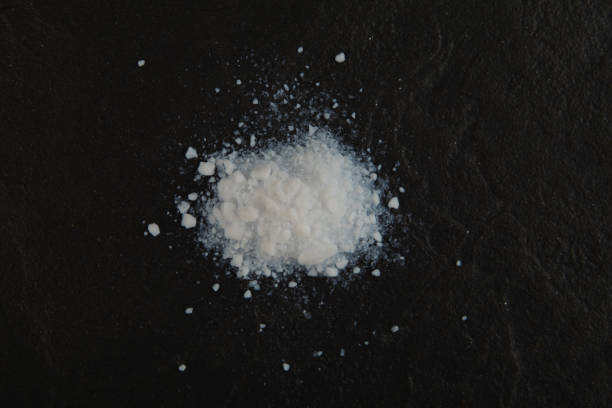 istock Pile of Colloidal silicon dioxide on black stone surface, top view. Enterosorbent. Powder for preparation of suspension to relieve a hangover after holidays, poisoning or intoxication 2196821034
