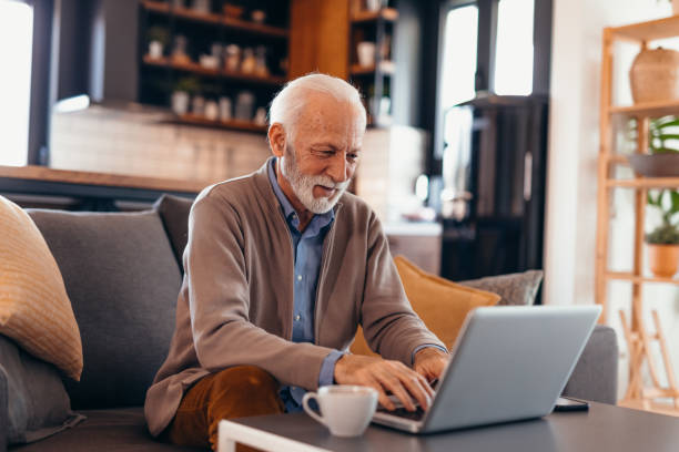 istock Senior man working on laptop at home sitting on sofa 2196821248