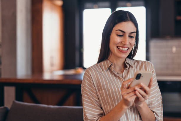 istock Young businesswoman using mobile phone and smiling at home 2196821313