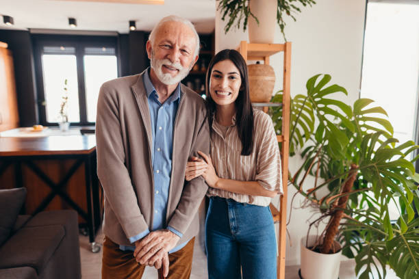 istock Young woman assisting elderly man with walking cane at home 2196821344