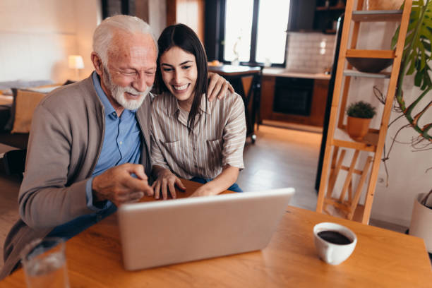 istock Senior man and young woman using laptop at home 2196821347