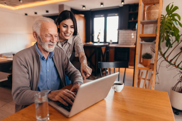 Senior man learning how to use laptop with his daughter
