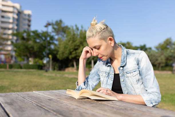 relaxed happy woman on a wooden bench on a green meadow with trees