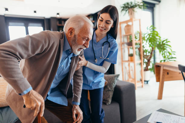 istock Nurse assisting elderly man getting up from sofa at home 2196821675