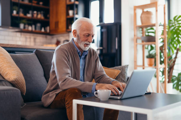 istock Senior man using laptop on sofa in living room 2196822502