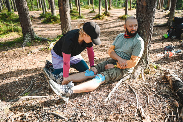 istock Two hikers take a break at a forest camp, attending to a minor injury while surrounded by nature. 2196826510