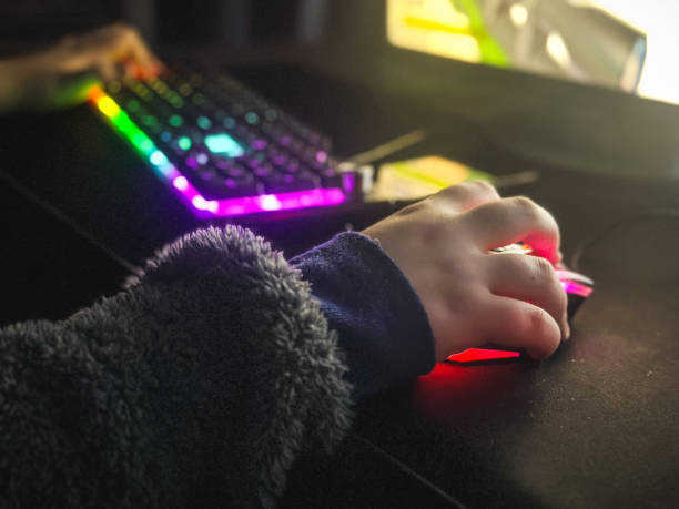 istock Close-up of boy's hands while playing computer games with RGB computer keyboard and mouse. 2196827634