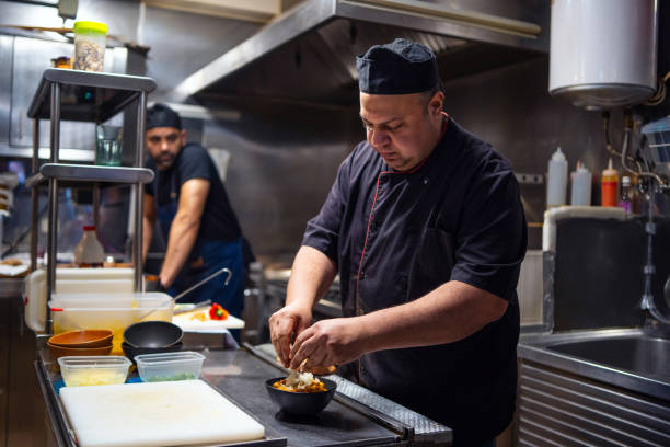 istock Chef concentrating on preparing a meal in a busy commercial kitchen, adding a final touch to a dish 2196828313