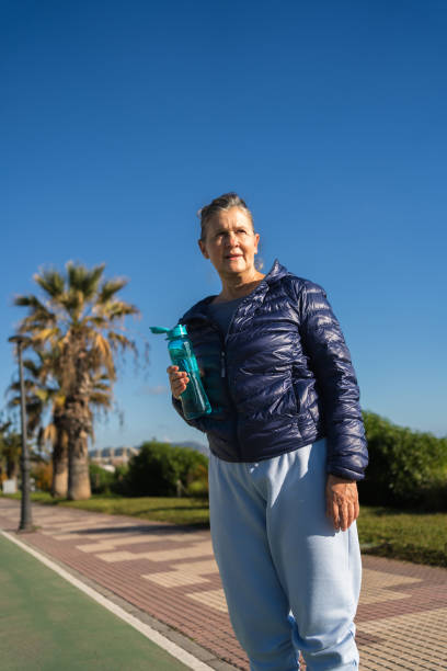 istock Senior woman holding water bottle while walking in a park 2196830871