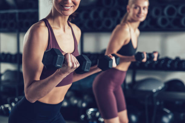 istock Two young caucasian women exercising with dumbbells and looking focused 2196830934
