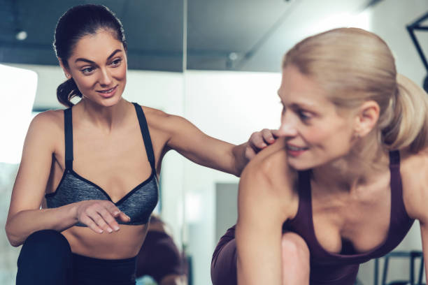 istock Dark-haired young coach training her blonde customer and both looking involved 2196830971