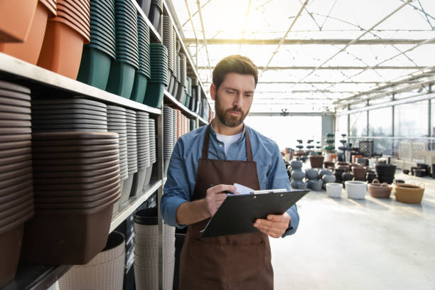 istock Male garden center worker in plants pot department making notes 2196833779