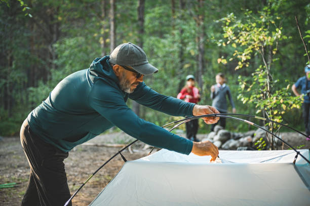 istock mature man sets up tent at campsite in forest 2196834238