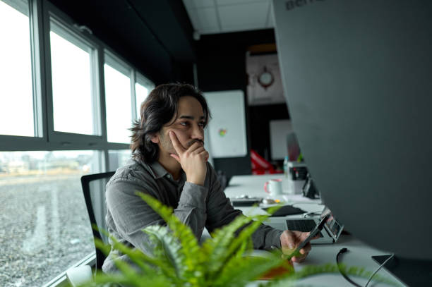 istock Young adult businessman is thinking about a new project at work 2196836090