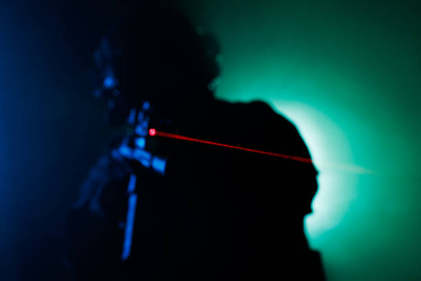 Silhouette of Person Aiming with Laser Sight Amid Dramatic Background