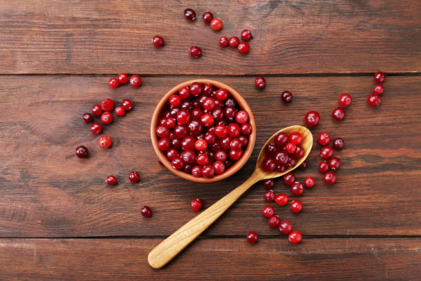 istock Fresh ripe cranberries in bowl and spoon on wooden table, flat lay 2196836458