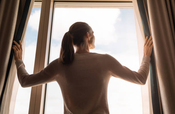 istock Woman opening curtains and letting sunlight in. 2196836484